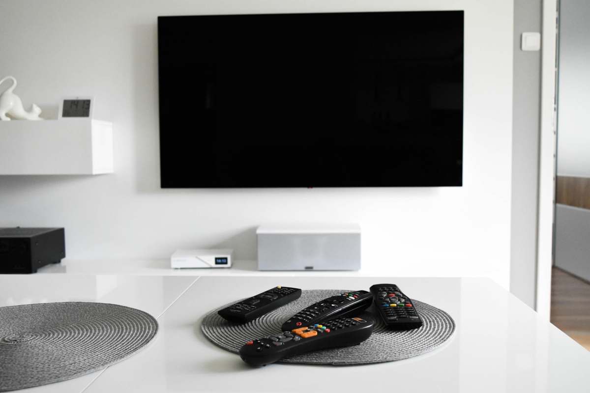 Telecomandi su tavolino e tv appesa alla parete