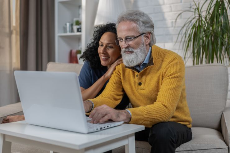 uomo e donna sorridenti di fronte al pc