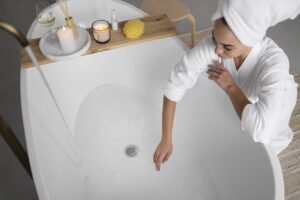 Donna in accappatoio che mette la mano dentro una vasca da bagno