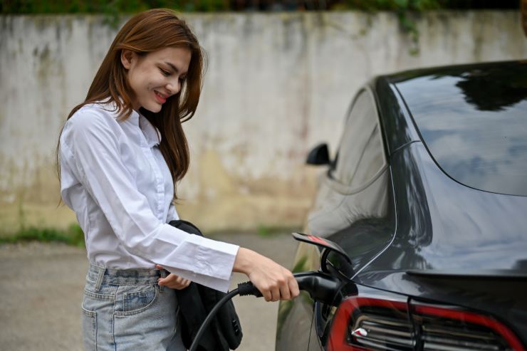 donna sorridente ricarica auto elettrica