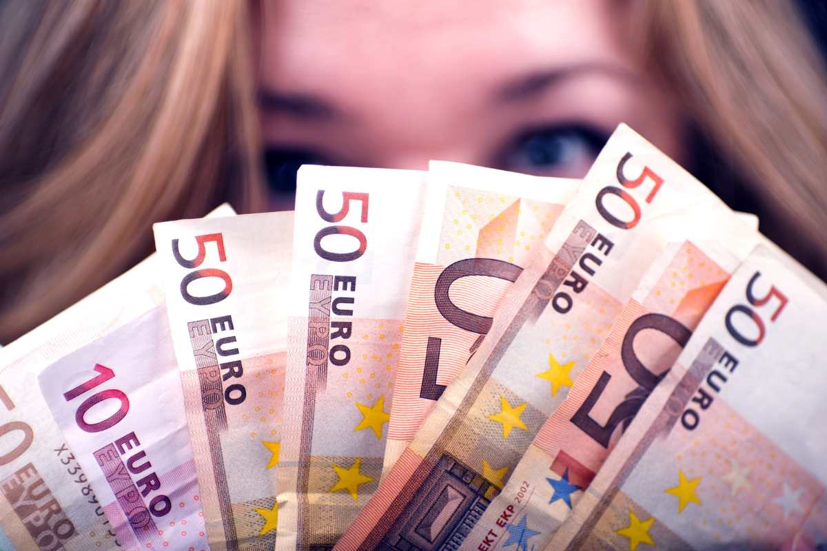 donna di cui si vedono solo gli occhi tiene in mano banconote euro