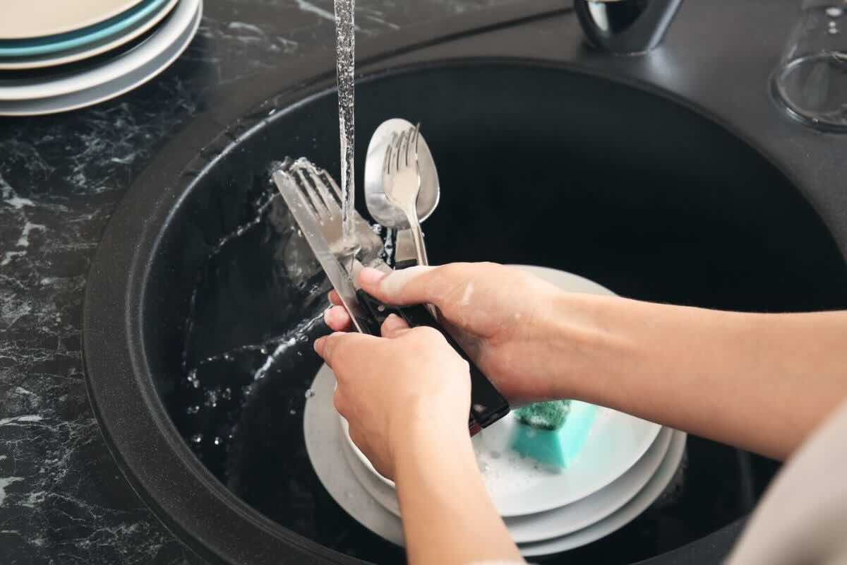 Lavare posate sotto acqua correte, piatti nel lavandino