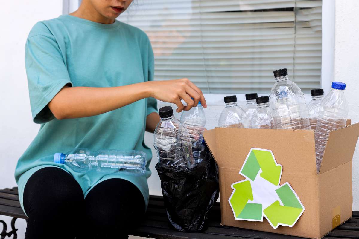 donna con bottiglie di plastica tra i rifiuti