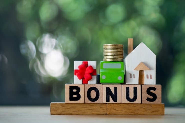 scritta bonus con in miniatura casa pacco regalo auto e monete