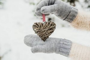 Guanti di lana che reggono un addobbo a cuore